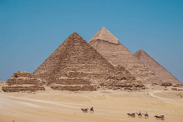 Tourists on camels in front of the Pyramids of Giza, Egypt