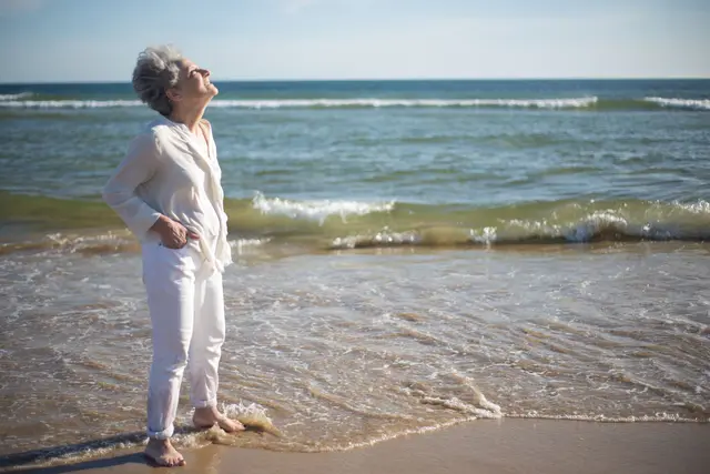 Senior woman traveling solo on a beach, relaxed and confident.